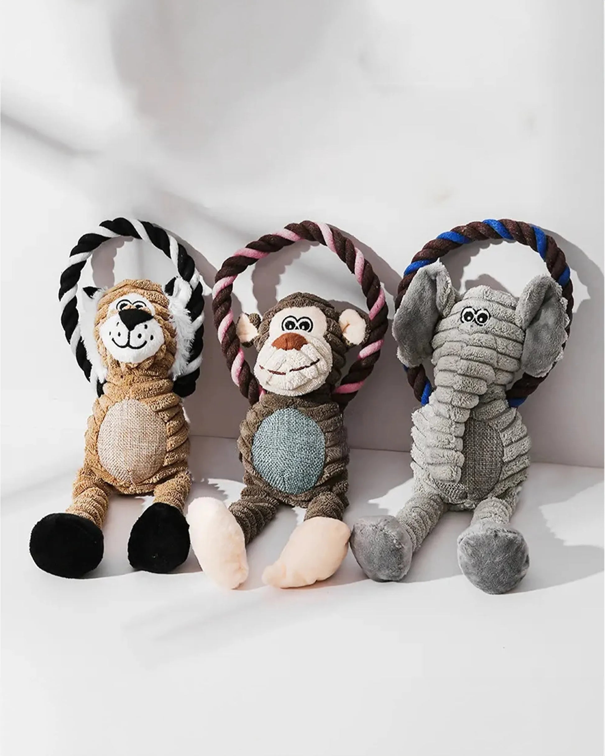 Tres juguetes de peluche para perros con forma de animales (un león, un mono y un elefante) con un anillo de cuerda.