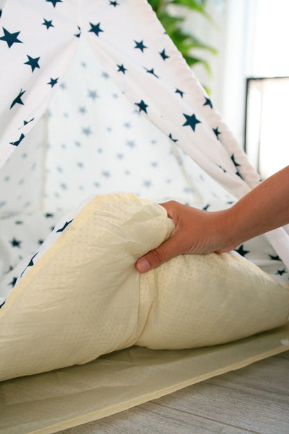 Mano levantando el cojín de la carpa blanca con estrellas azules.